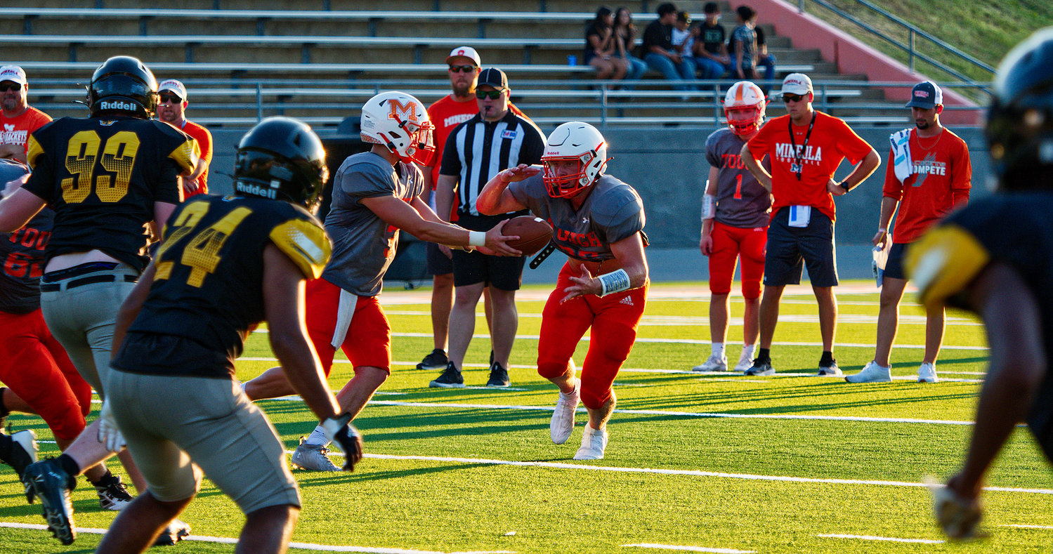 The Mineola offense tries a running play with T.J. Moreland handing to Dawson Pendergrass, under the watchful eye of the coaches during Friday’s scrimmage against Winona.